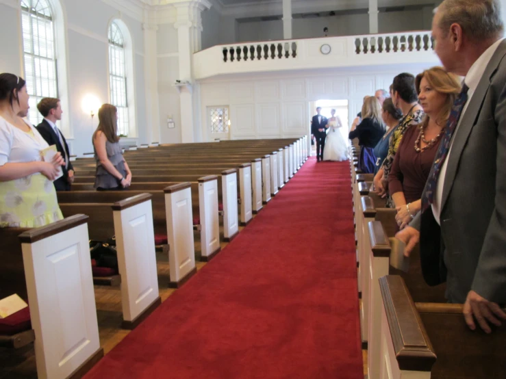 several people are standing in pews of the church