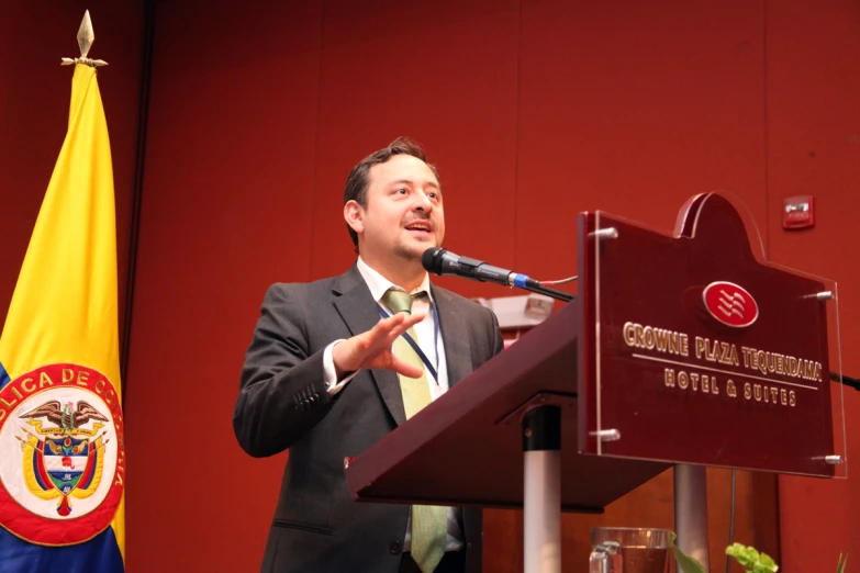 a man speaking at a podium while wearing a suit