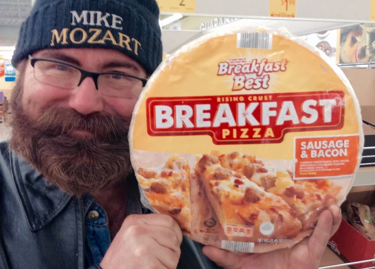 the man is holding a package of breakfast pizza