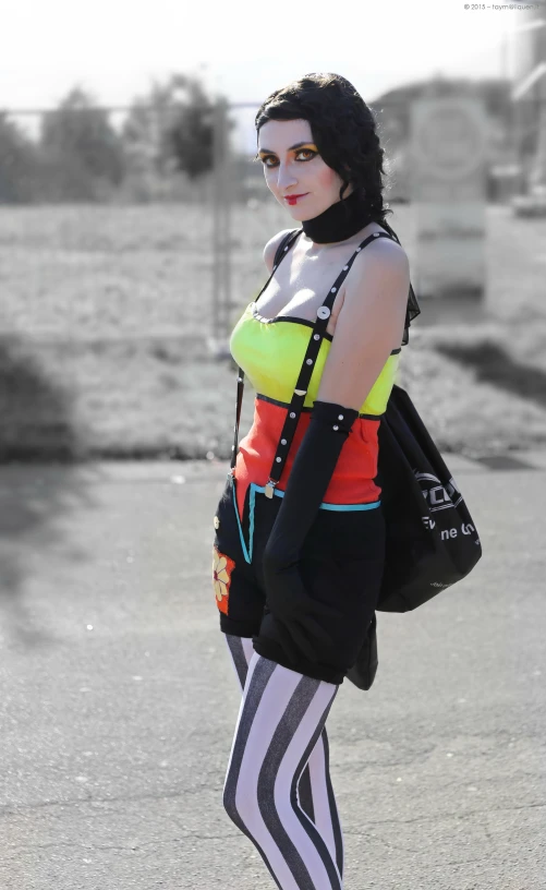 a woman wearing black and white striped tights, an orange top and yellow vest