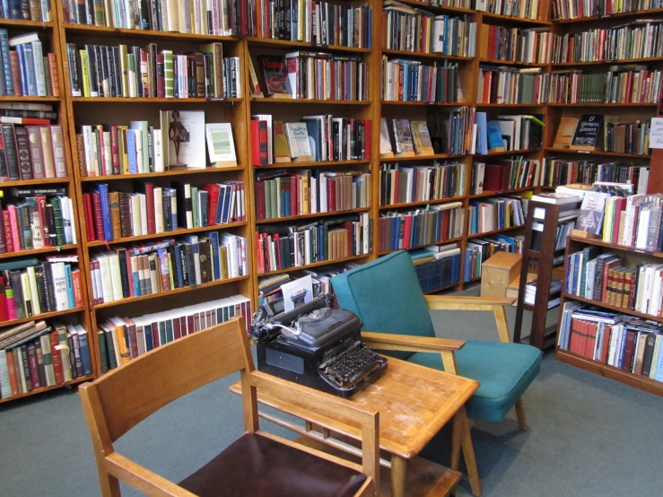 liry with lots of books and furniture and a typewriter on a desk