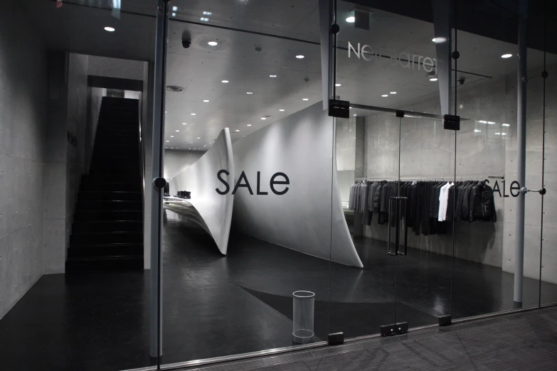 a store with an sale sign written on it and clothes displayed in the window