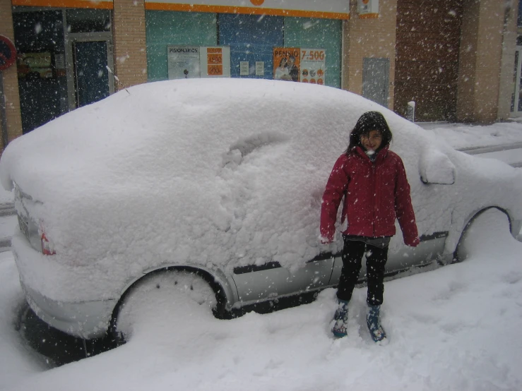 a child is standing in front of a car covered with snow