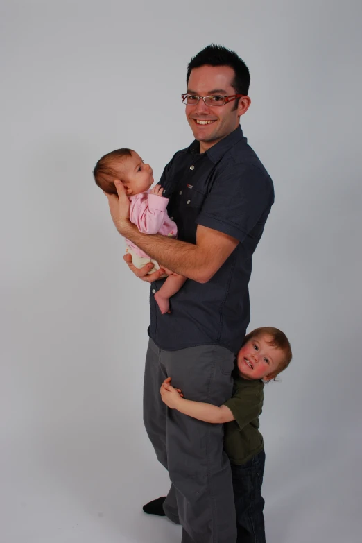 a man is holding two babies in his arms