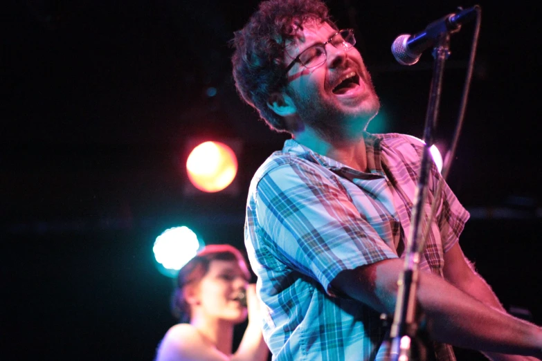 a man standing at a microphone and holding a guitar