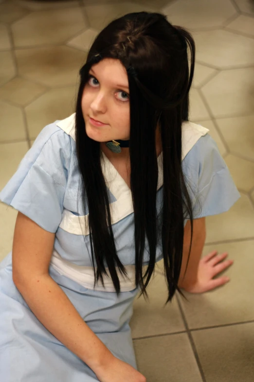 a woman wearing an apron with long black hair sitting on the ground