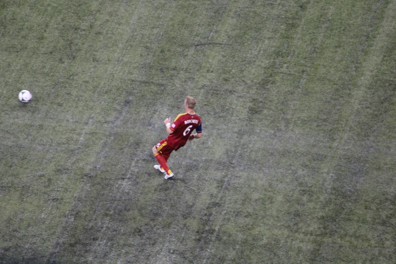 the soccer player is in red and yellow kicking the ball