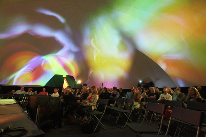 an outdoor audience is shown during a light show