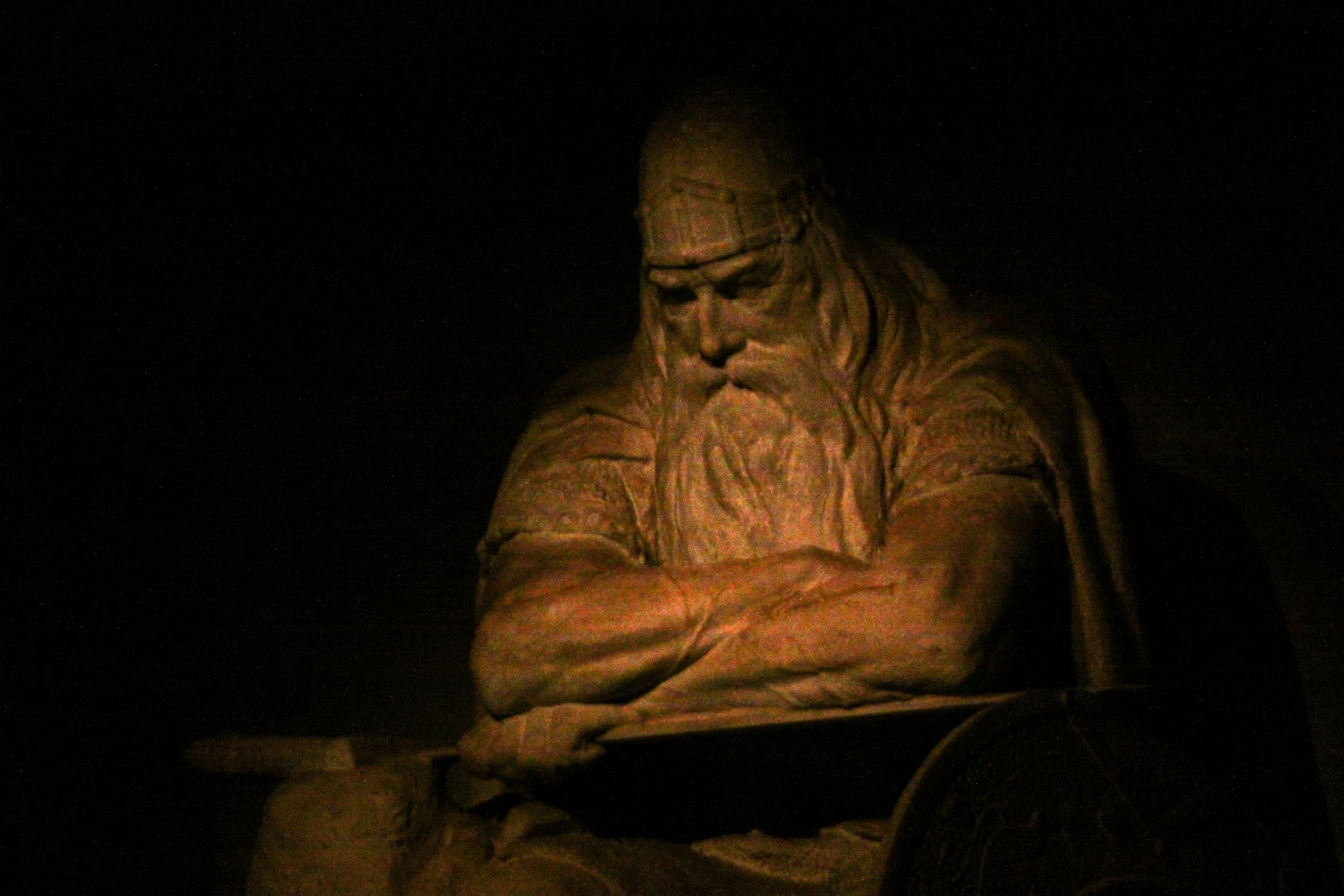 a statue in the dark holding a phone