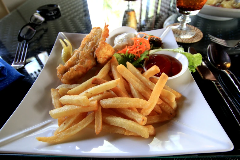 a plate full of fries, salad and ketchup on a table