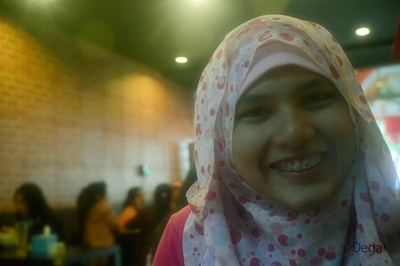 smiling woman wearing a head scarf in a restaurant