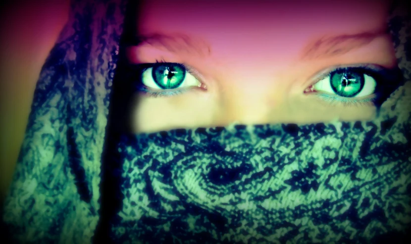 a girl with big green eyes hiding behind a scarf
