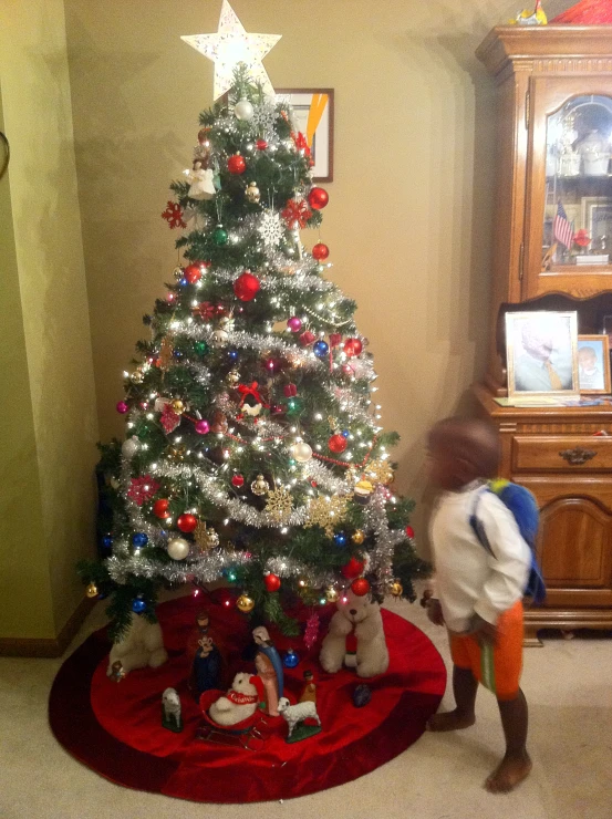 a small child is standing in front of a decorated christmas tree