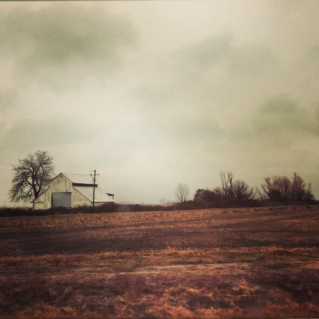 a small white house sitting on top of a dry grass field