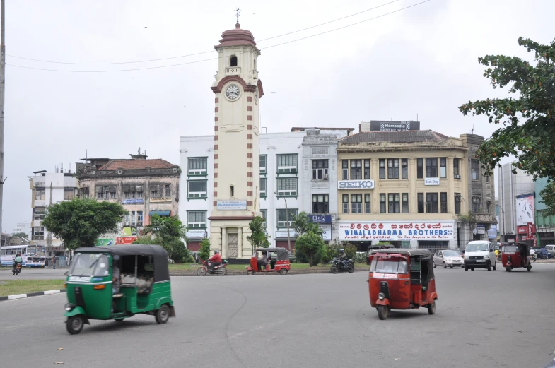 two tuk tuks with a clock tower in the background
