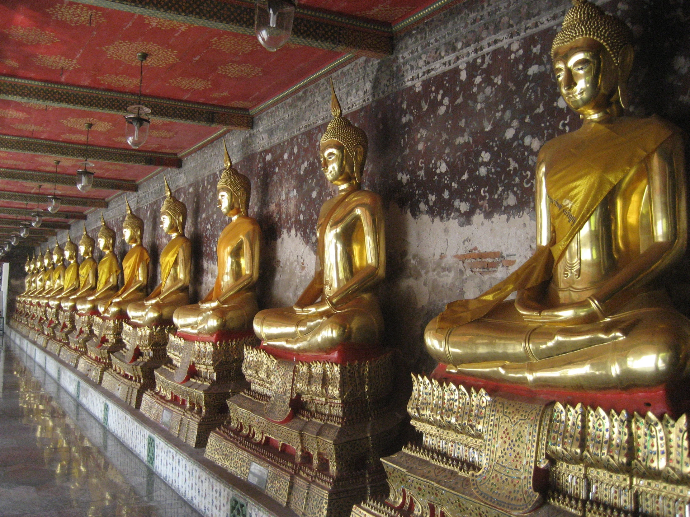 gold statues of buddhas line the walls in a temple