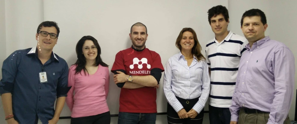 a group of smiling people posing in front of a sign