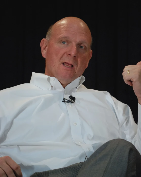 a bald man with a tie sitting in a chair