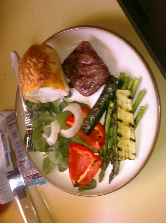 a plate with food that includes asparagus, steak, and grilled bread