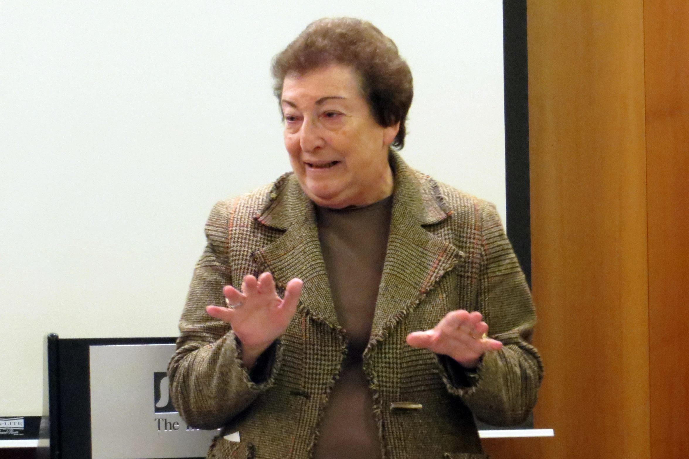 an old woman in a business suit making gestures