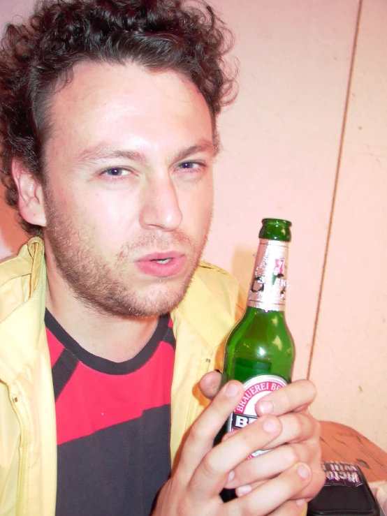 a man holding a bottle in his left hand and wearing a yellow jacket