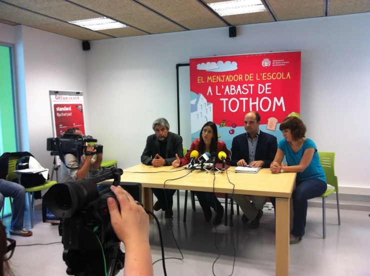 four people sitting at a table with microphones