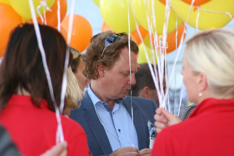 a man standing in a group of people holding balloons