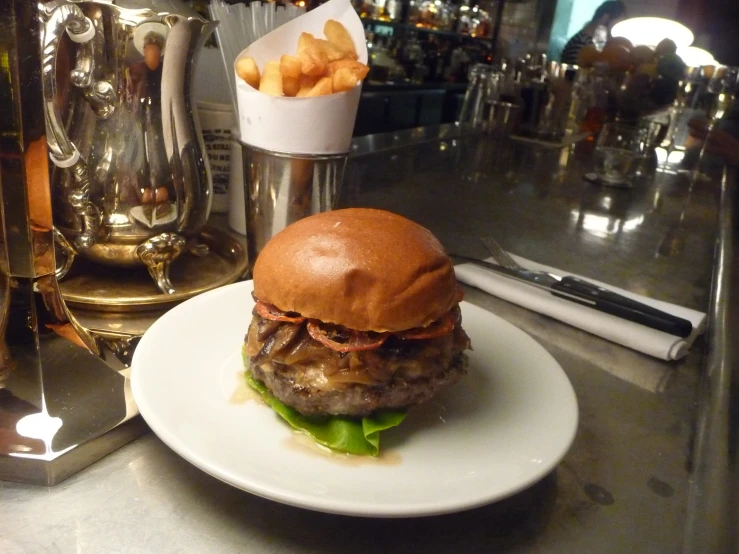 a steak sandwich with fries and a shaker on a bar