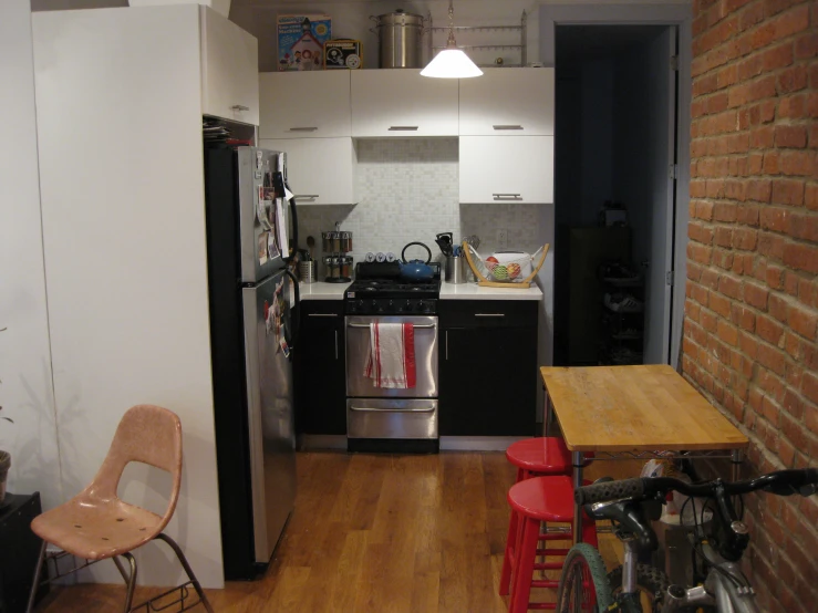 a small kitchen with brick wall, wood floor and stove