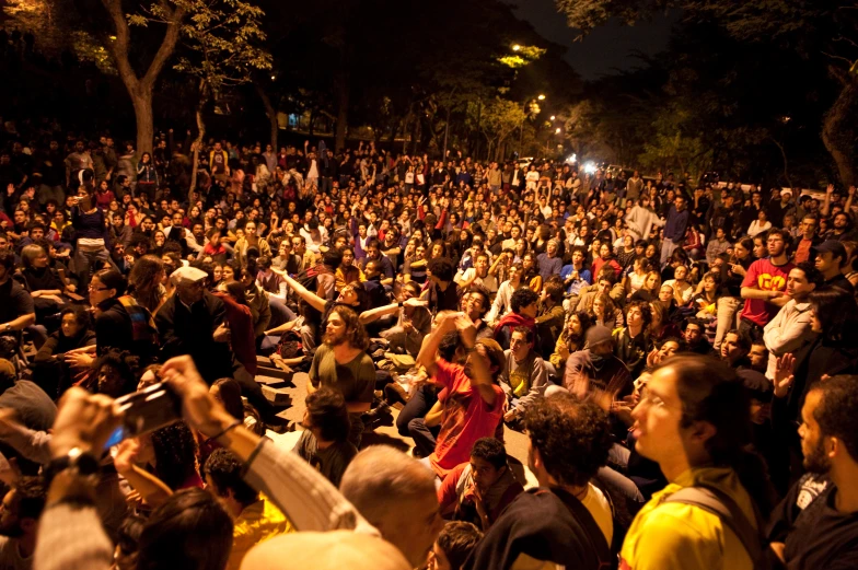 a crowd in the dark sitting on some benches