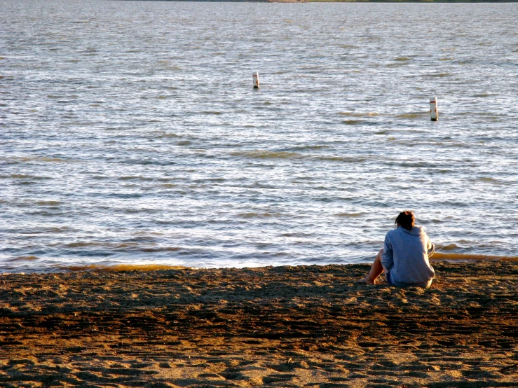 the woman is sitting on the beach alone