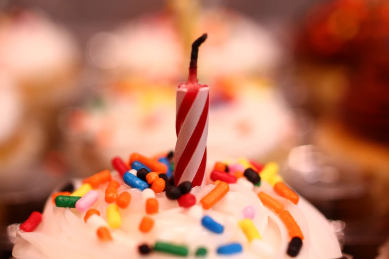 a candle sticking out of a cake with sprinkles