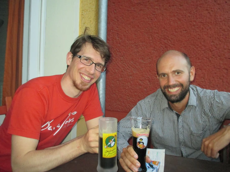 two men are holding their drinks in each hand