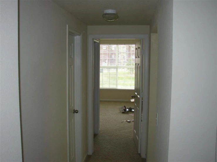 the room has a white door and a long hallway with three mirrors