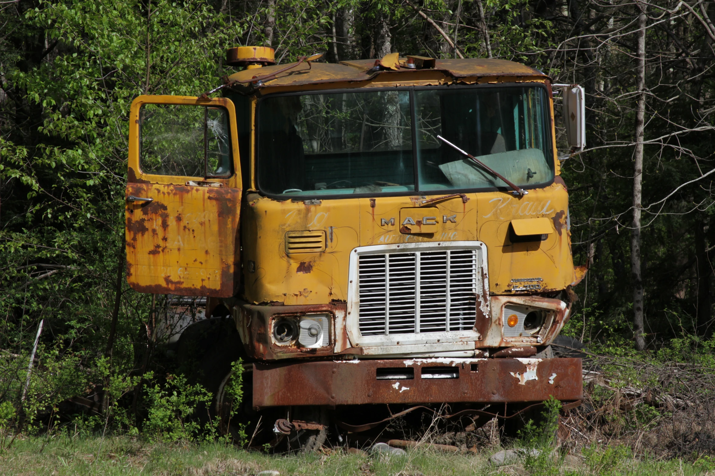 an old yellow truck sitting in the middle of a field