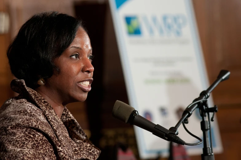 woman standing at a microphone in front of a speaker