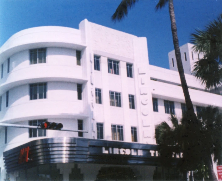 the large white building has palm trees in front