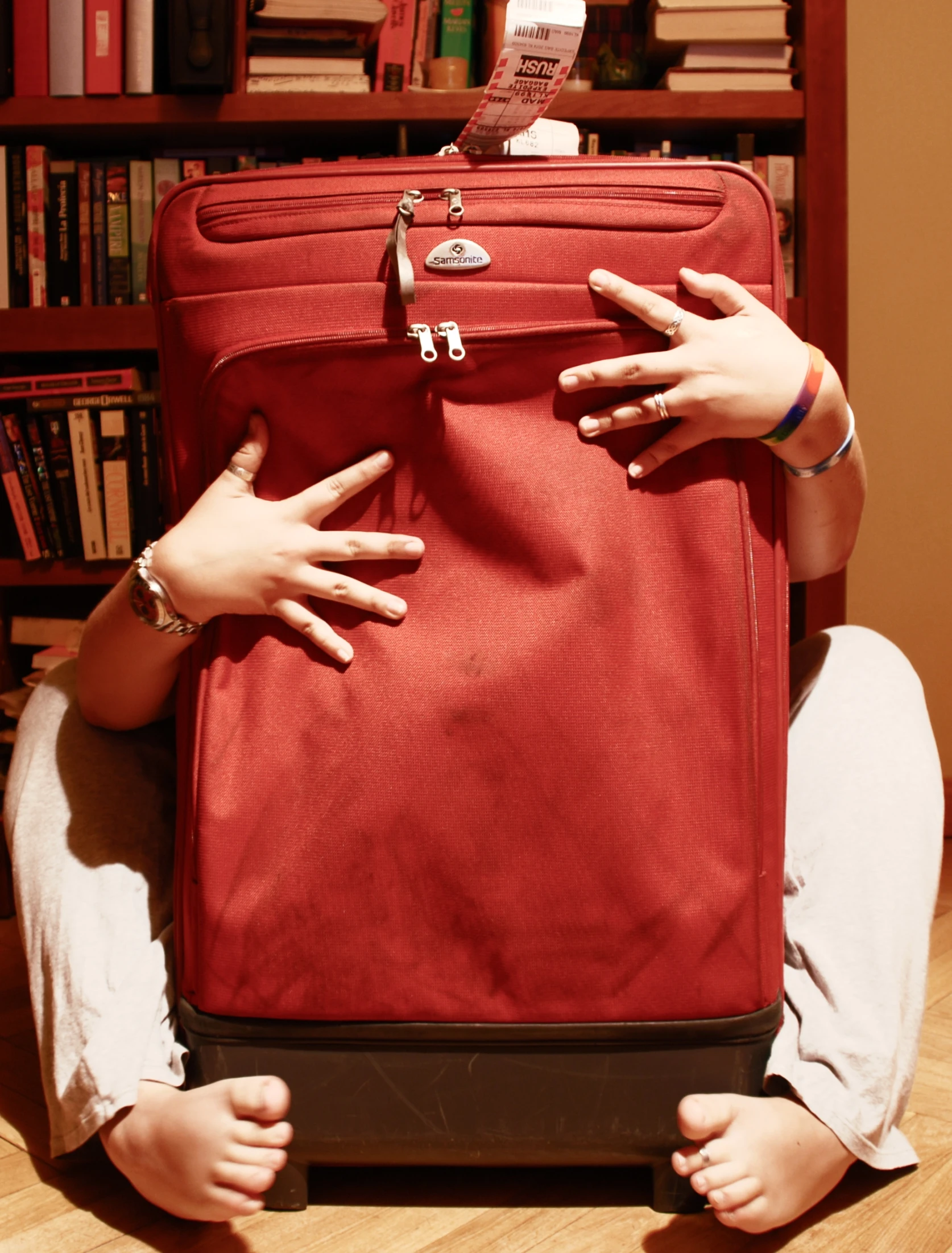 a woman has their arms around a red suitcase