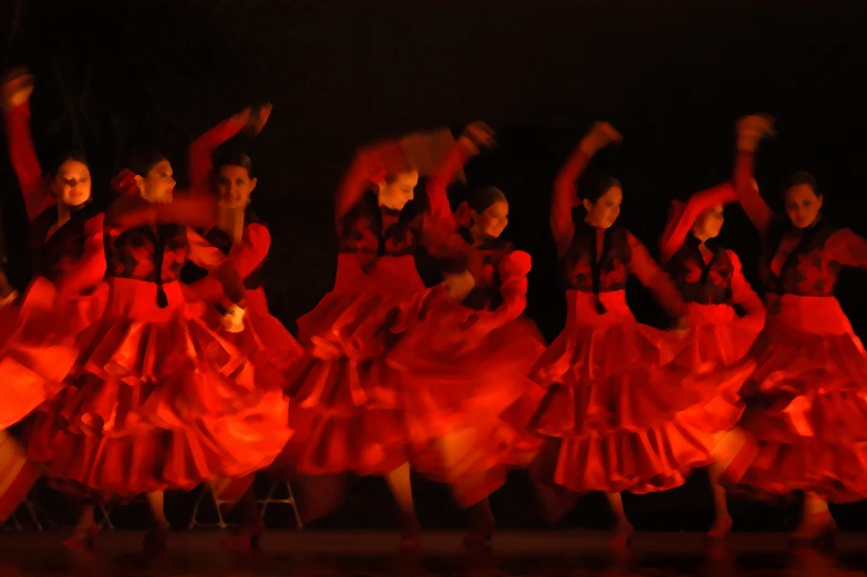 blurred image of dancers in motion with colored light on a black background
