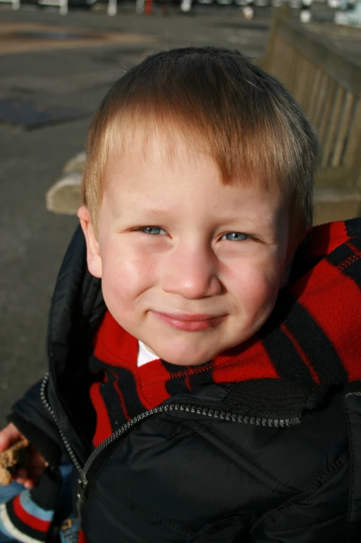 a little boy in a black coat and a red hood