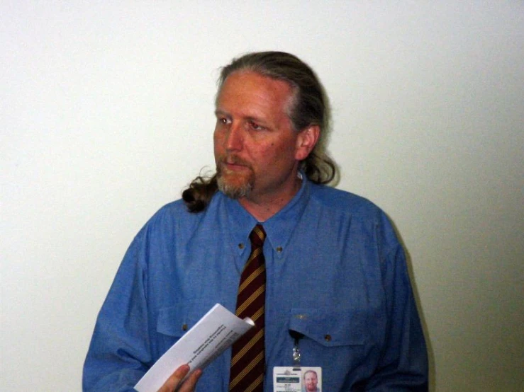 a man is dressed in a blue shirt and tie with a hairdow
