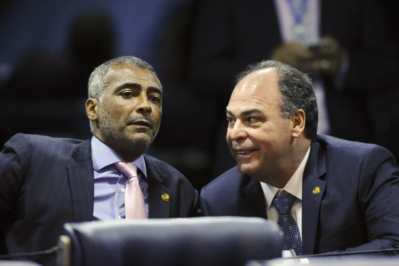 two men sitting next to each other in front of a crowd