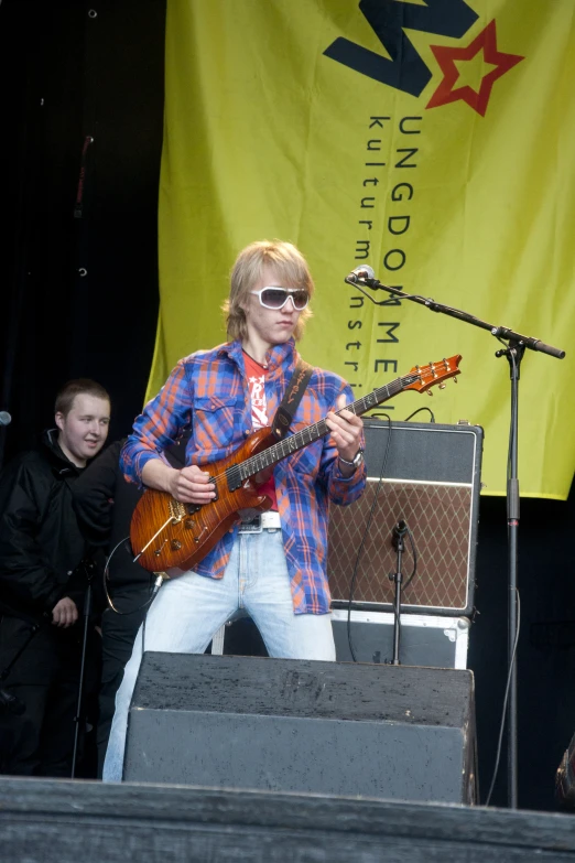 a man with shades on and playing guitar on stage