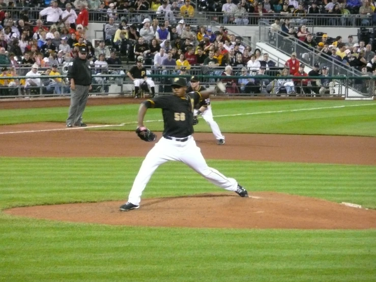 baseball pitcher in the middle of a pitch with spectators watching