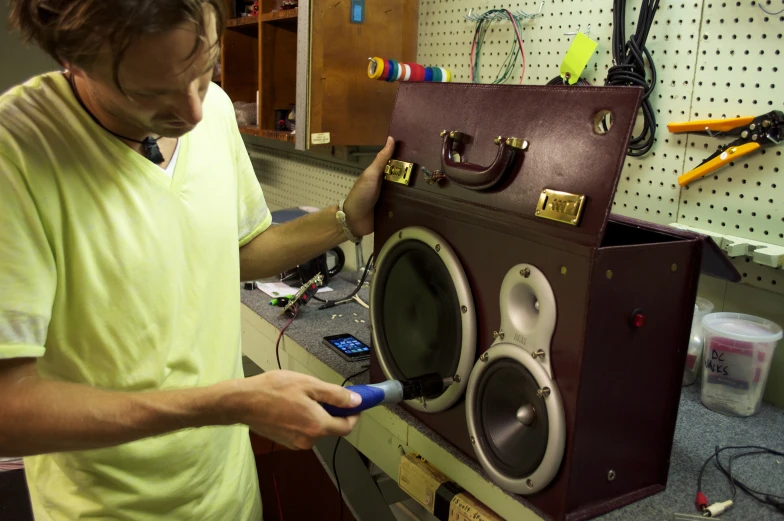 man holding a device in front of a speaker that he is making