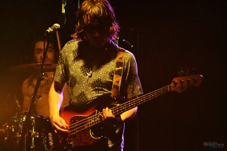 a man playing bass guitar at night with other musical instruments