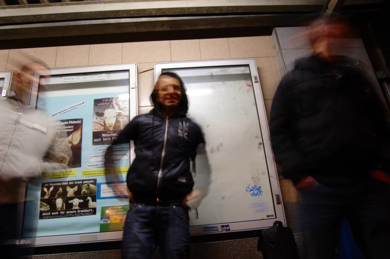 some guys standing in front of an advertit on the side of a building