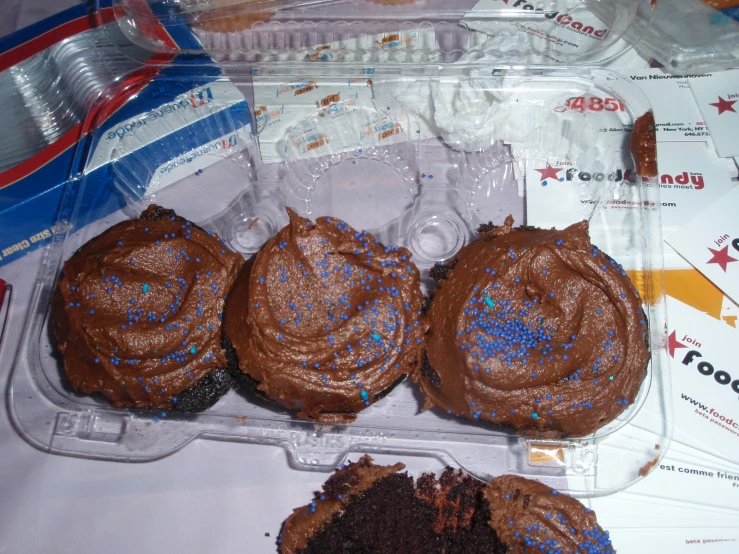 three decorated cakes in an empty plastic case