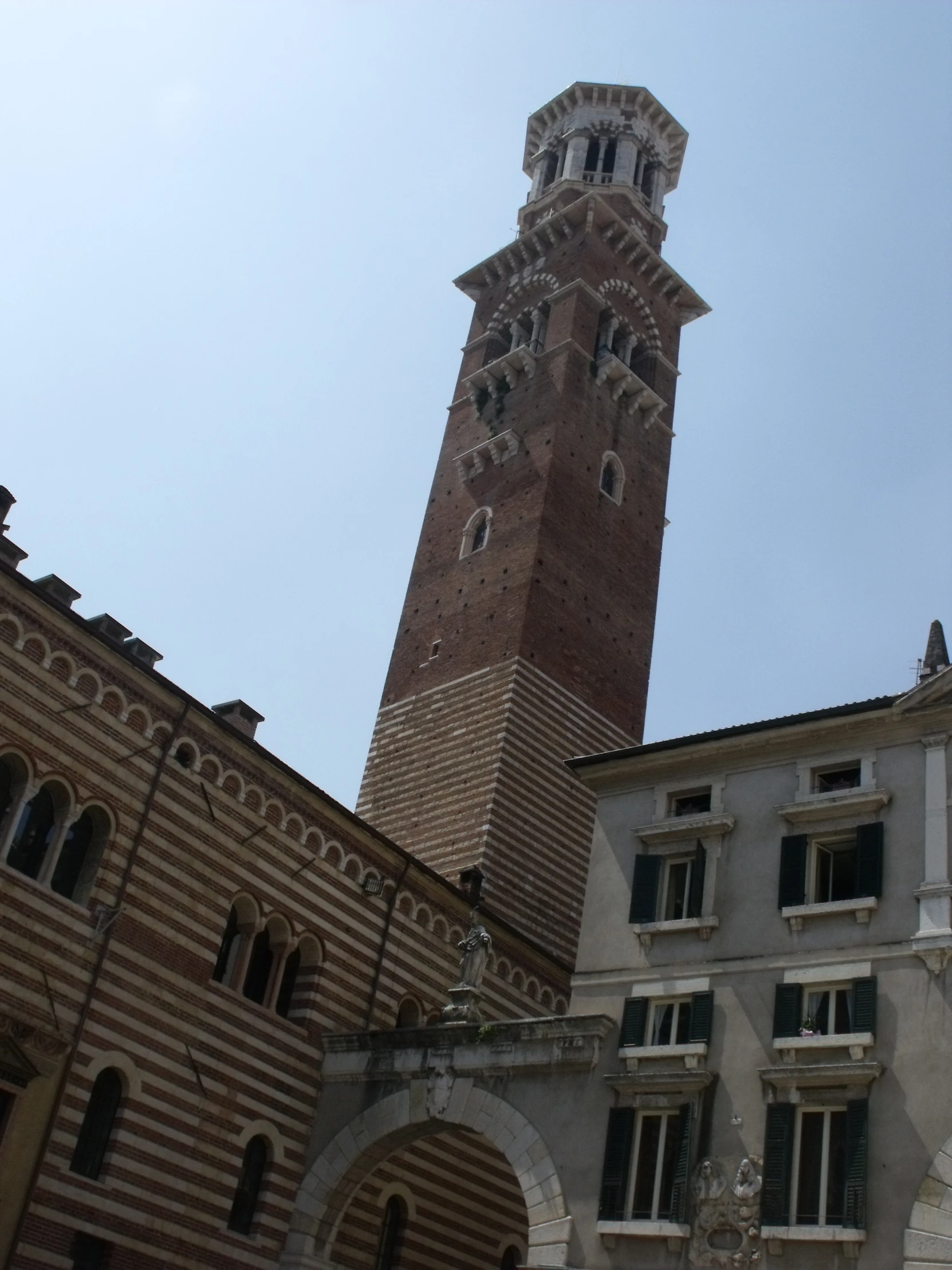 a tall brown brick clock tower next to an old stone building