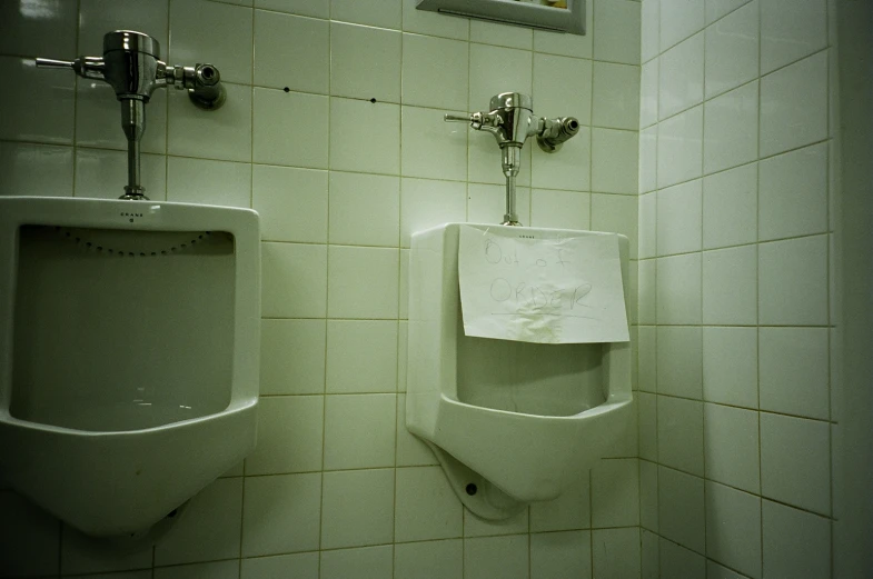 two urinals in the corner of a bathroom stall